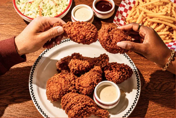 Hands sharing a plate of Blue Ribbon fried chicken