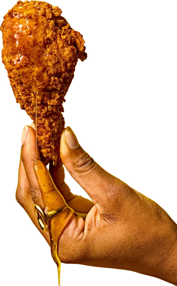 Hand holding a piece of fried chicken